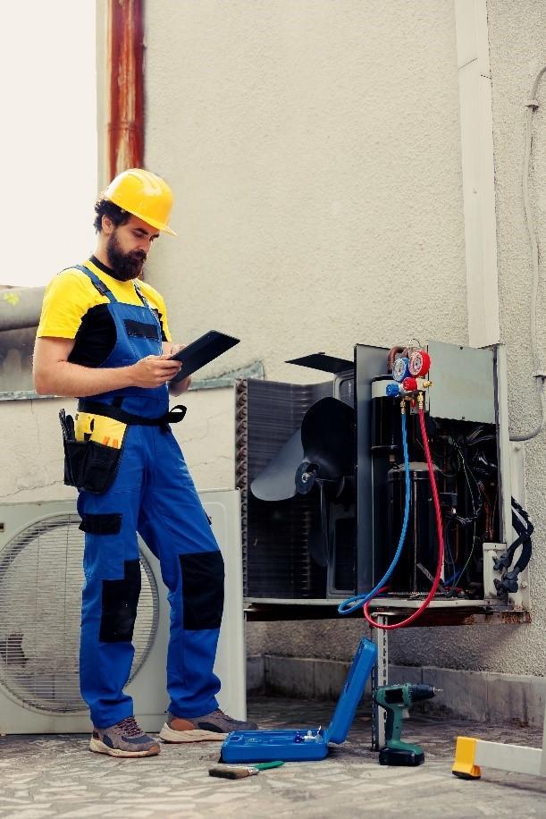 HVAC technician inspecting and servicing a commercial air conditioning unit during routine maintenance.