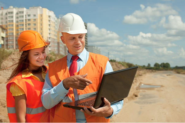 Contractor and project manager reviewing construction plans on a laptop at a Long Island job site.