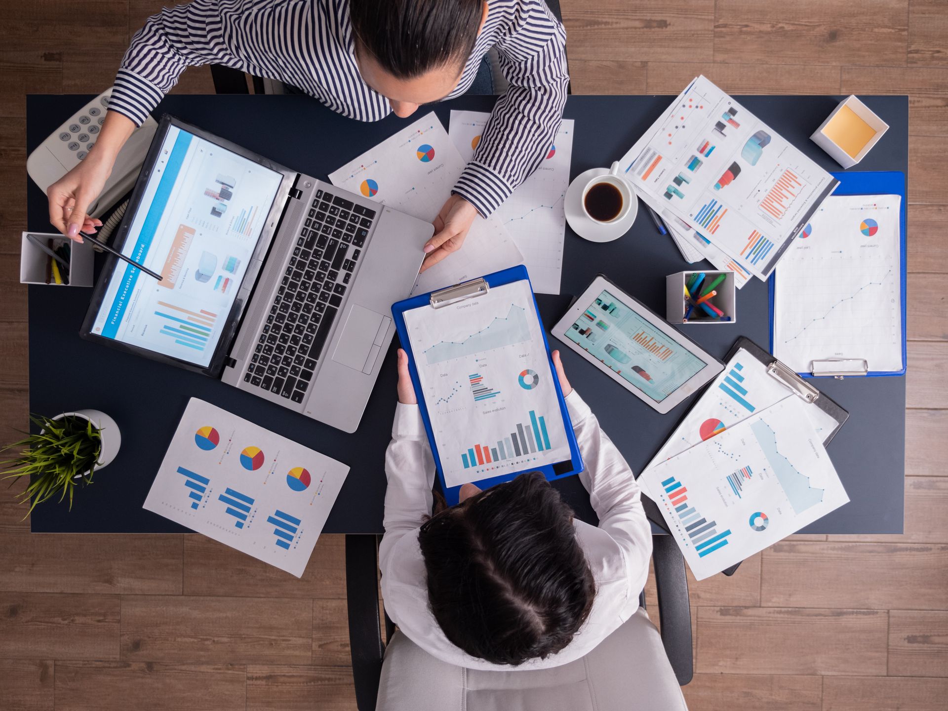 Top-down view of an seo company team analyzing client performance charts and data.