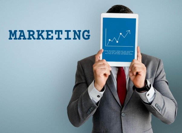 Businessman holding a tablet displaying upward marketing growth graph.
