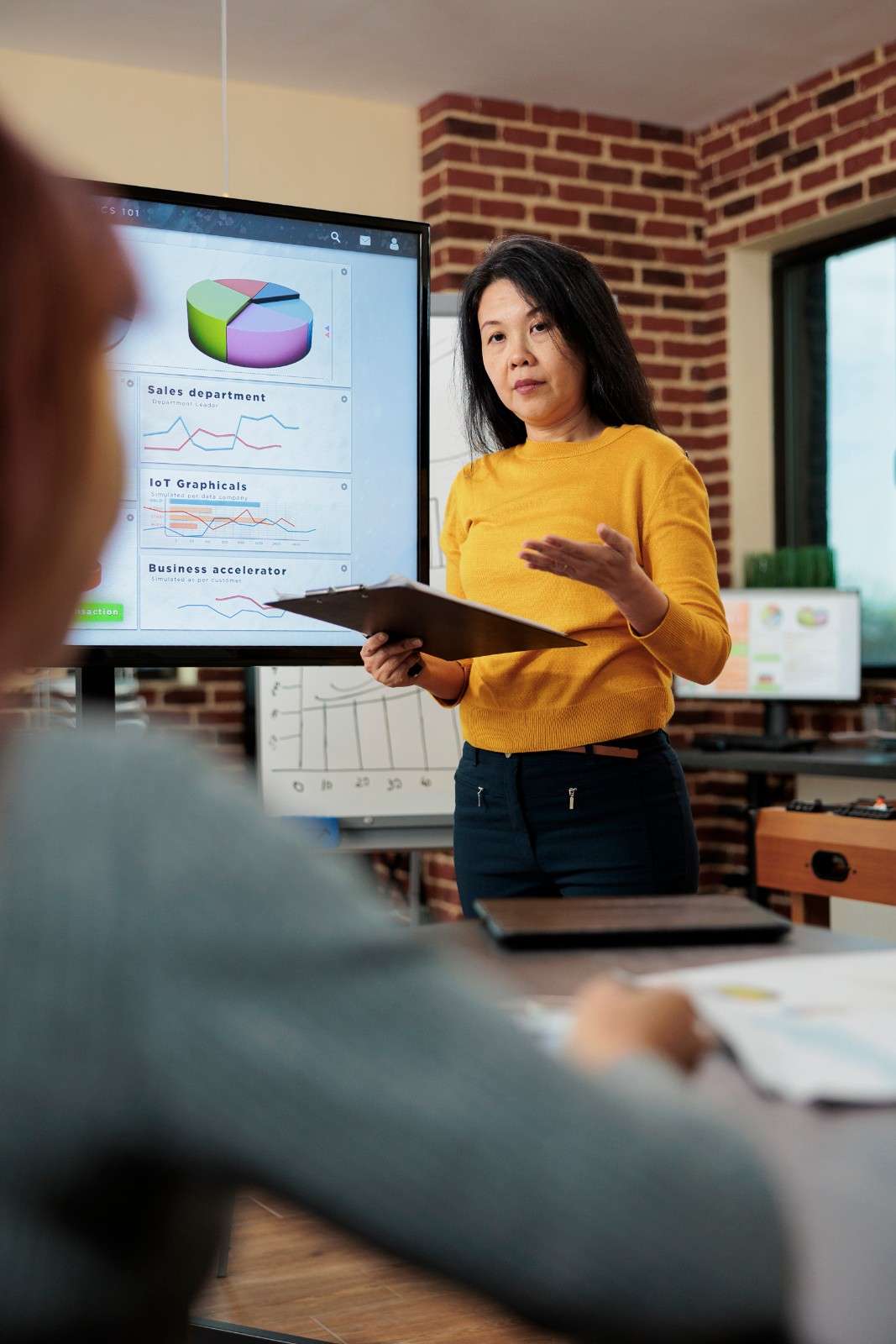 Female executive presenting digital marketing analytics and growth charts on a screen during an agency strategy meeting.