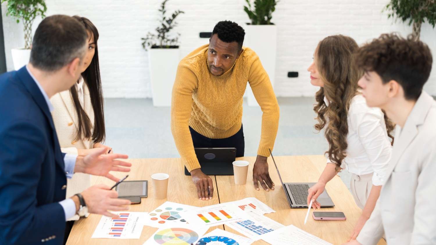 Diverse marketing team gathered around a table reviewing printed growth charts and performance reports