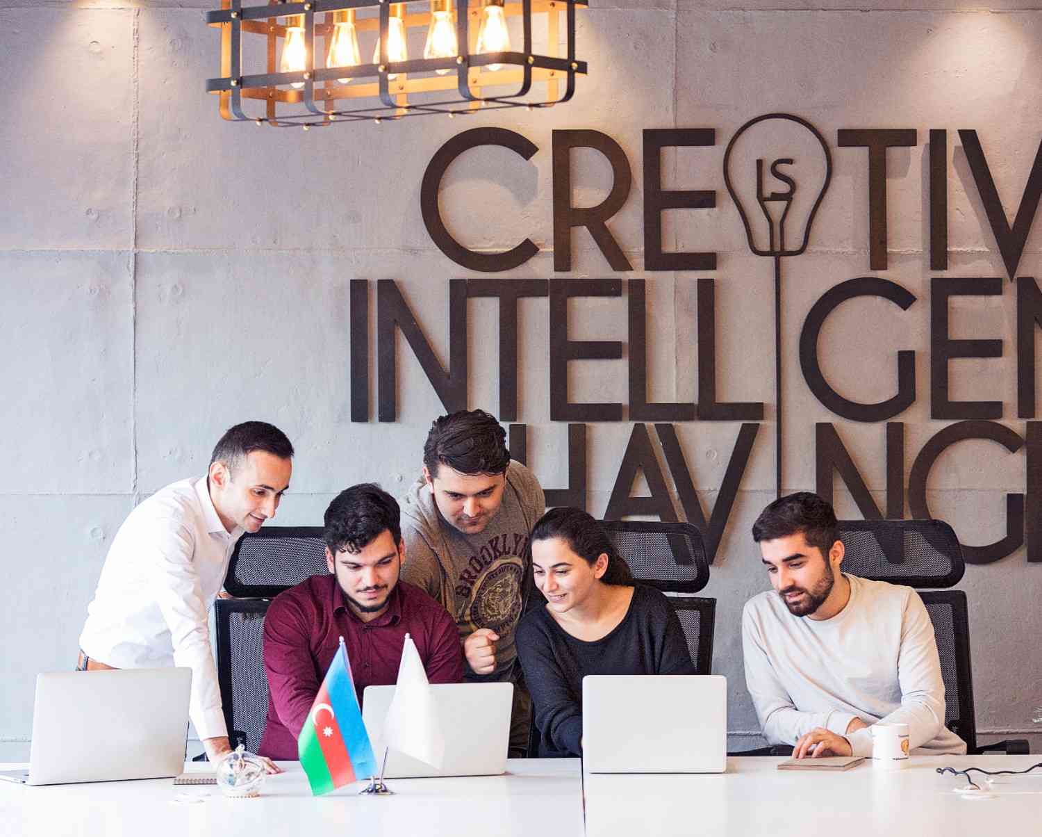 Creative digital marketing team collaborating together on laptops in a modern office.
