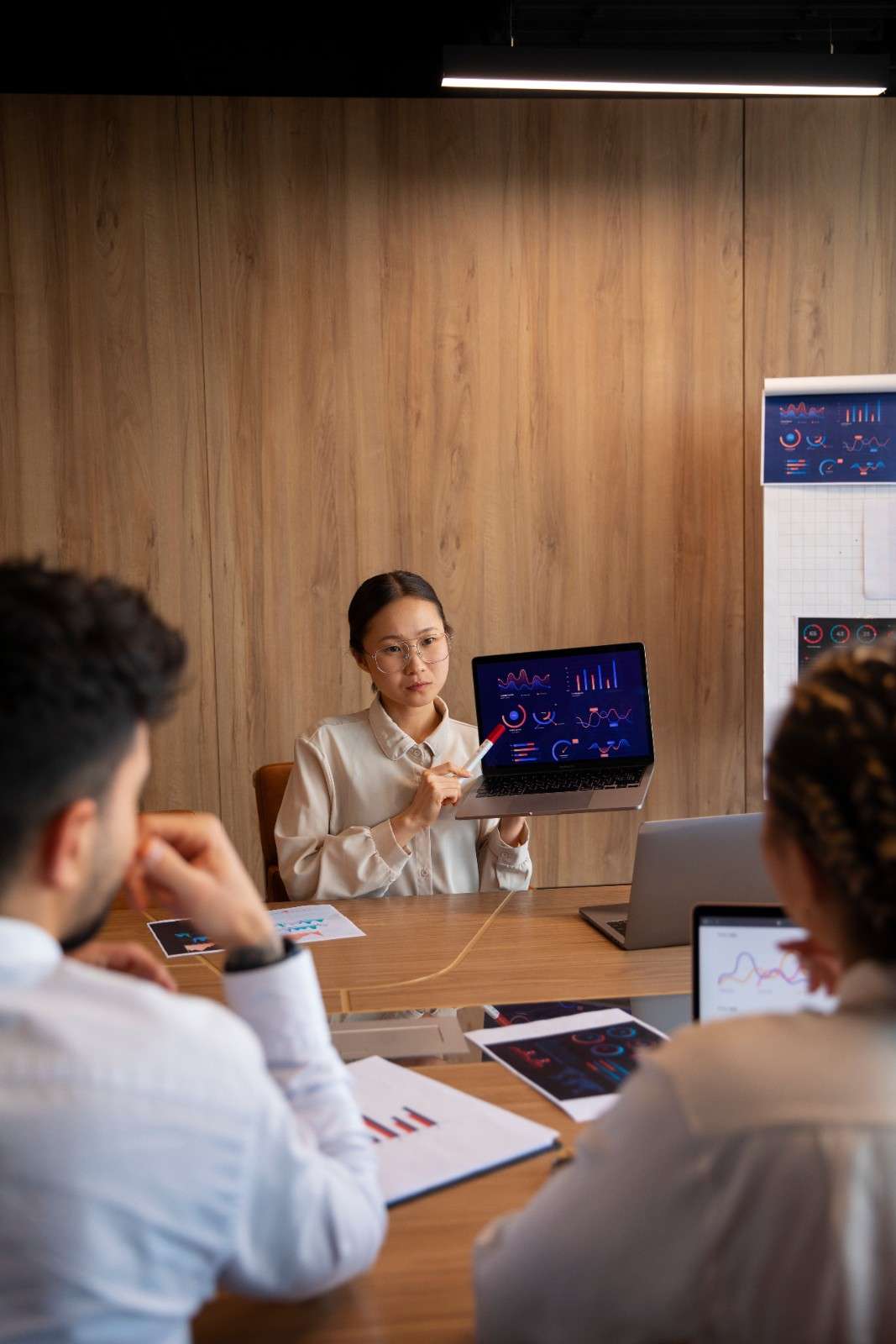 Colleagues reviewing digital marketing data and graphs on a laptop during a general team meeting.