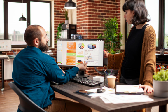 Business consultant reviewing financial data, expense tracking charts, and performance analytics on a laptop during a client strategy meeting.