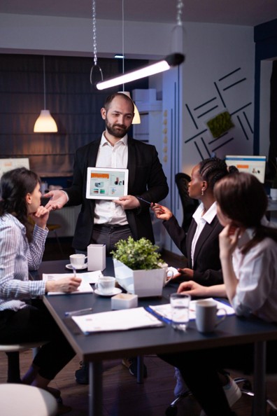 Marketing consultant presenting campaign analytics on a tablet to a business team.